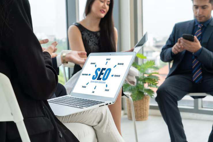 Business professionals discussing SEO Services along with strategies in UAE with a laptop displaying SEO-related terms.