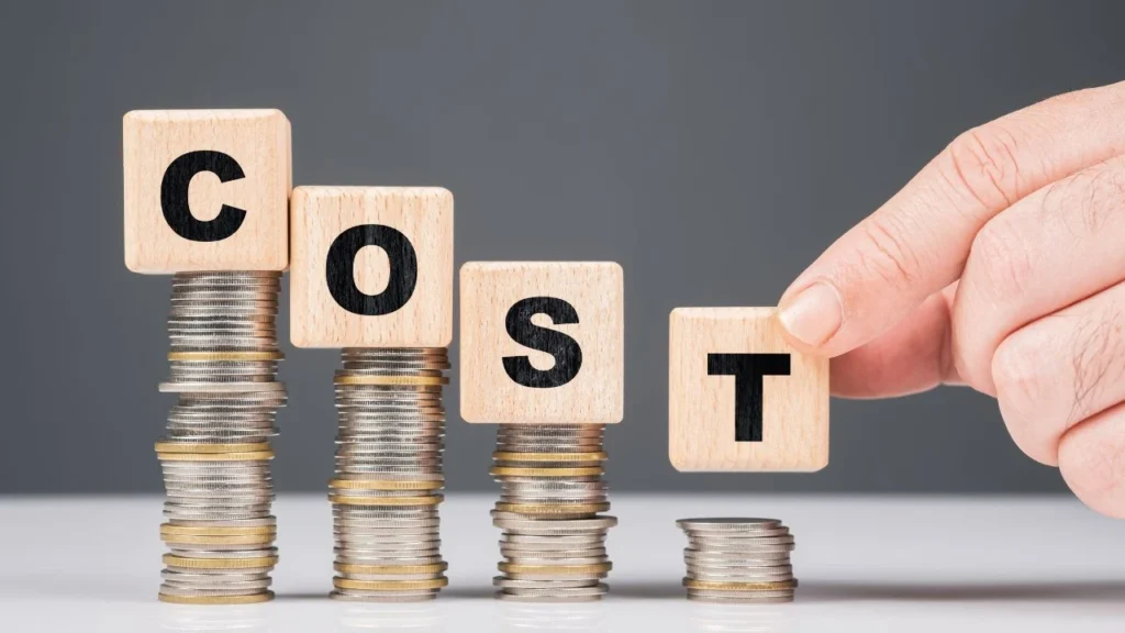 Concept image showing stacked coins and wooden blocks spelling COST, representing budget planning by a Dubai Marketing Agency.