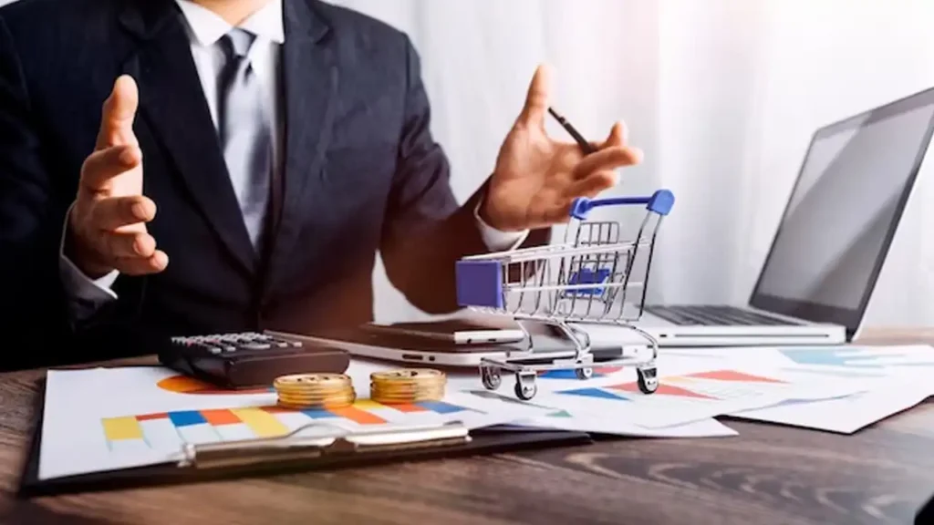 Businessman discussing digital marketing with a shopping cart on a desk, showing online business strategy.