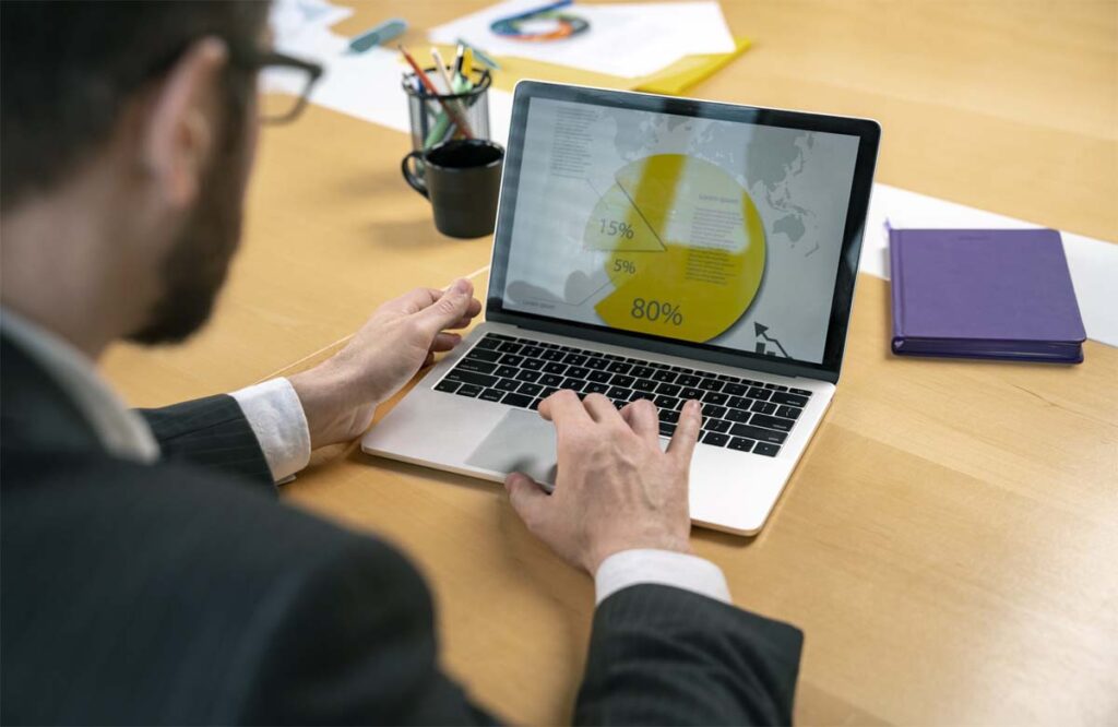 Man analyzing a pie chart on a laptop, reviewing data and performance metrics to guide Crafted Marketing Ads in Dubai for better campaign results.